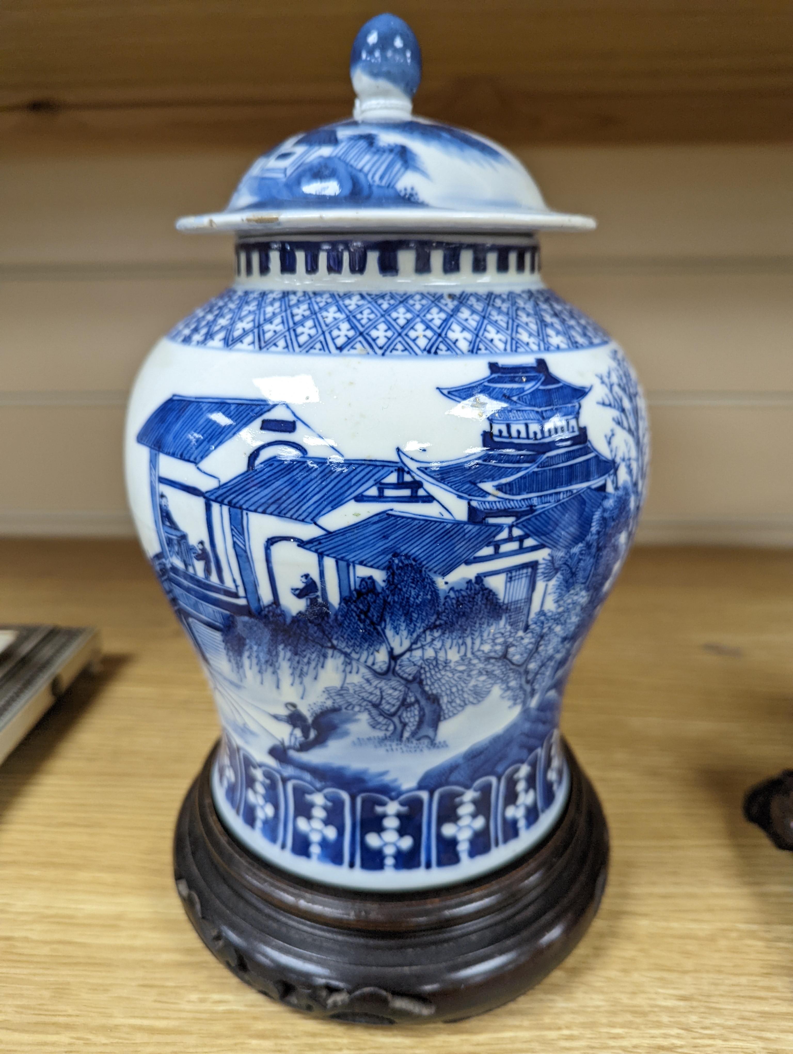 A late 19th / early 20th century Chinese blue and white landscape jar and cover, wood stand 30cm total height